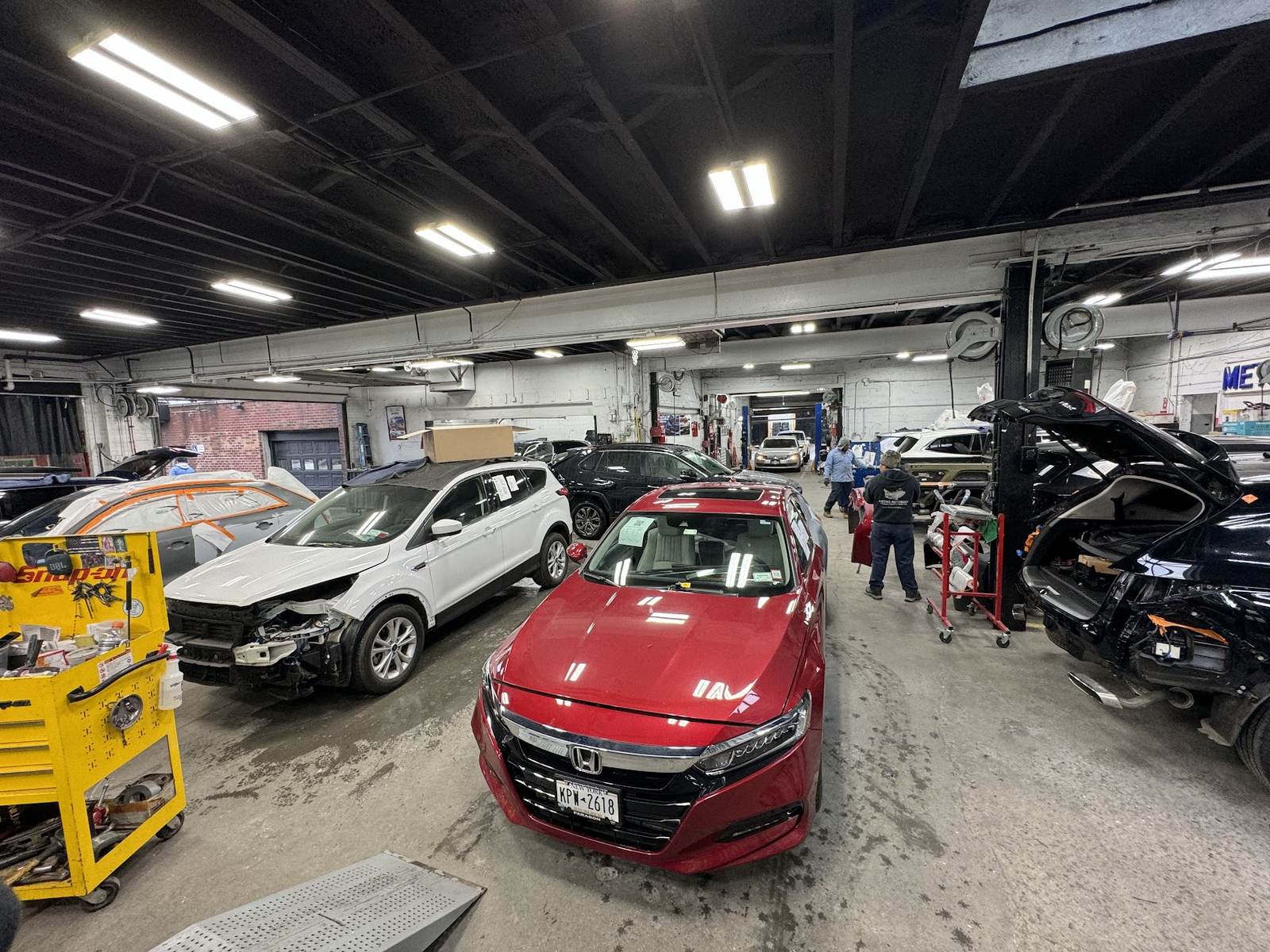 Metro Auto Body shop floor with multiple vehicles in for repair
