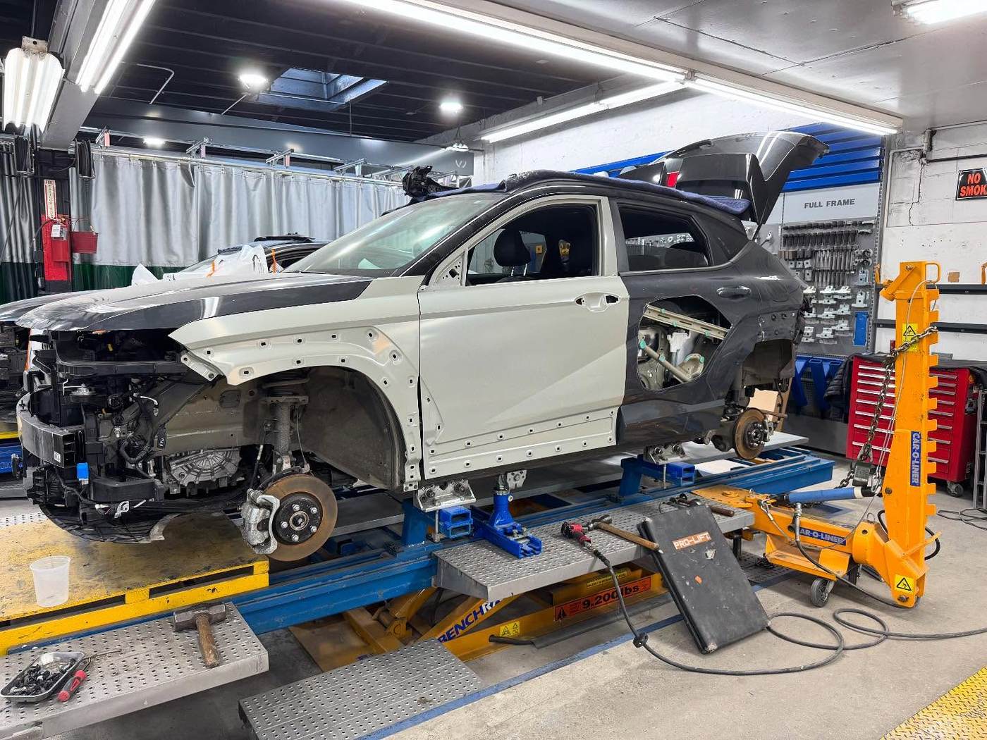 Vehicle on lift beside full tool wall at Metro Auto Body